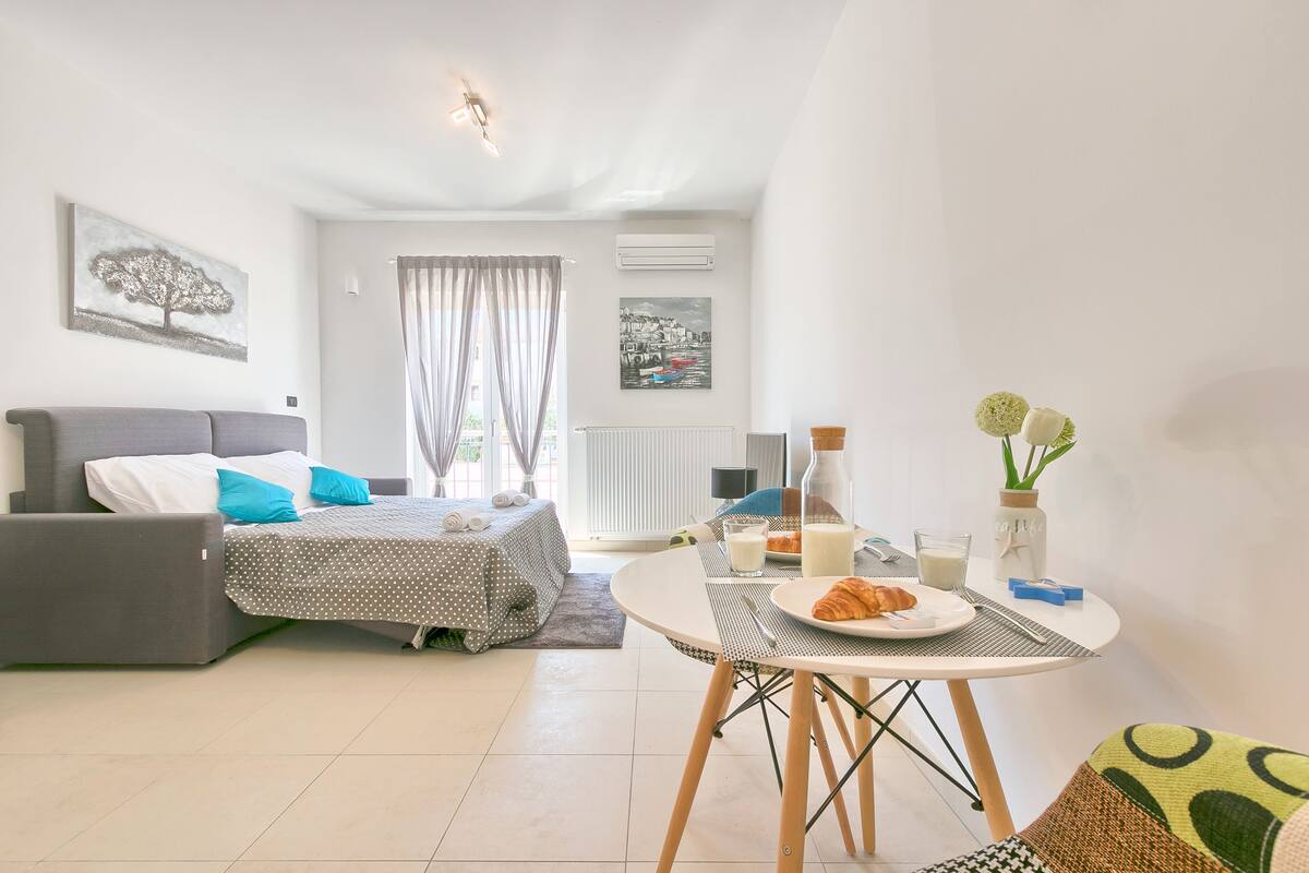 Ein modernes Schlafzimmer mit Bett, Nachttisch und einer Essecke, gedeckt für ein Frühstück.