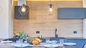 Una cocina moderna con protector de salpicadero de madera, una estufa integrada y una zona de comedor con una mesa dispuesta para dos.