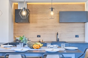 Eine moderne Küche mit Holzrückwand, einem eingebauten Herd und einem Essbereich mit Tisch für zwei Personen.