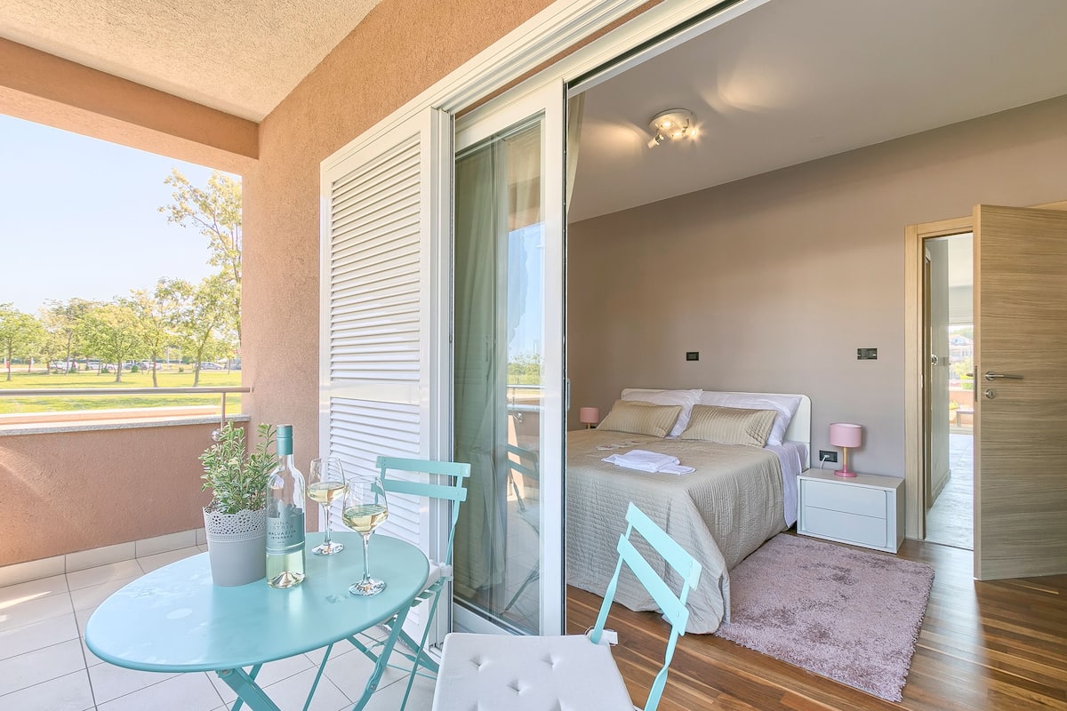Ein Schlafzimmer mit Bett, Nachttisch und Blick ins Freie.