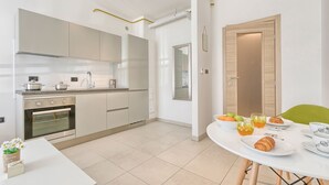 Una cocina moderna con horno empotrado, una mesa de comedor con productos para el desayuno y una silla verde.