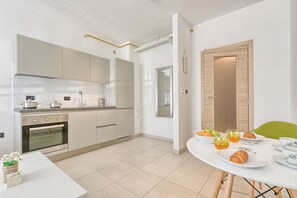 Eine moderne Küche mit Einbauofen, einem Esstisch mit Frühstücksgebäck und einem grünen Stuhl.