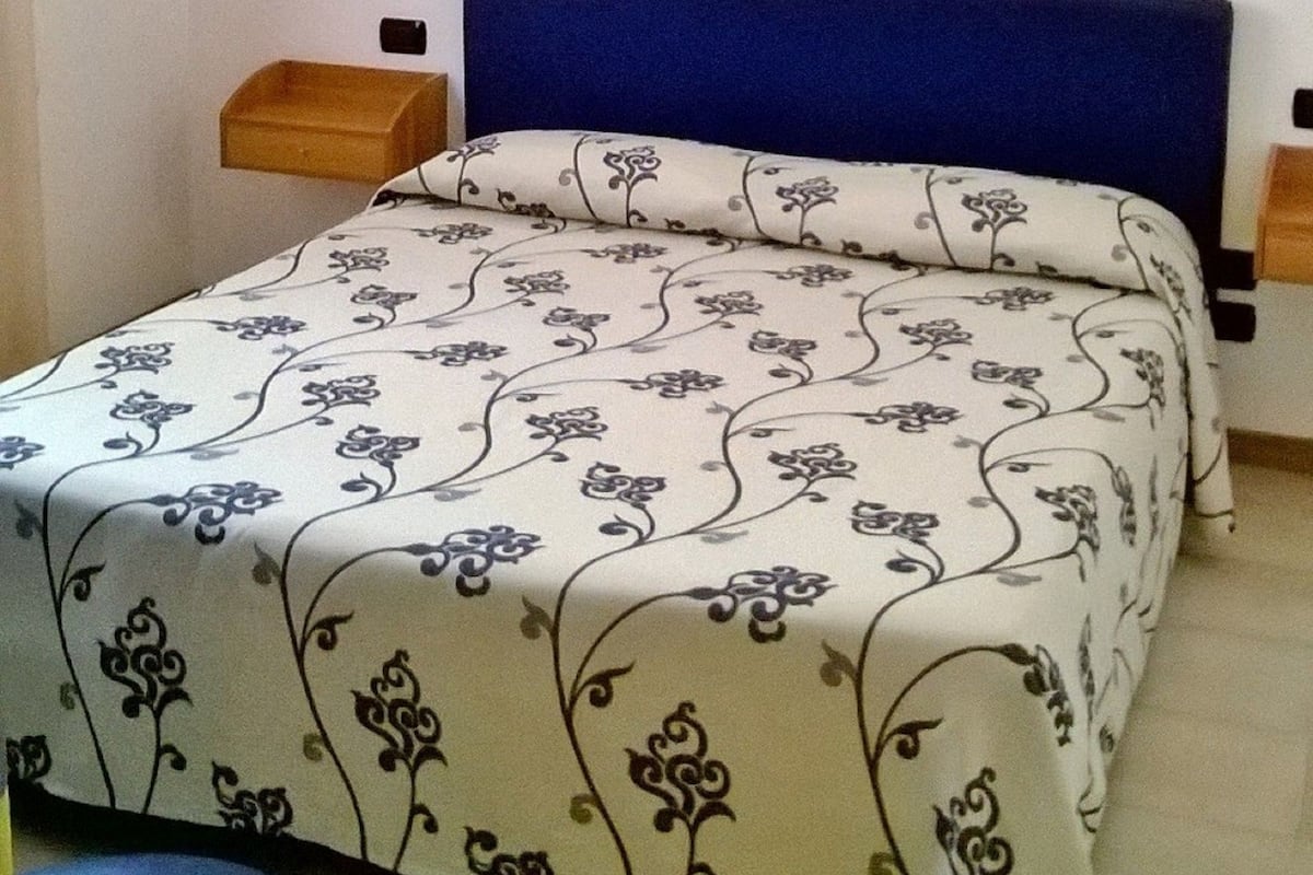 A simple bedroom with a bed, a chair, and two bedside tables.