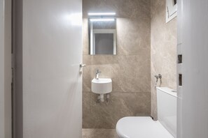 A bathroom with a white sink, a mirror, and a toilet. - Victoria Best Apartments (Athens)