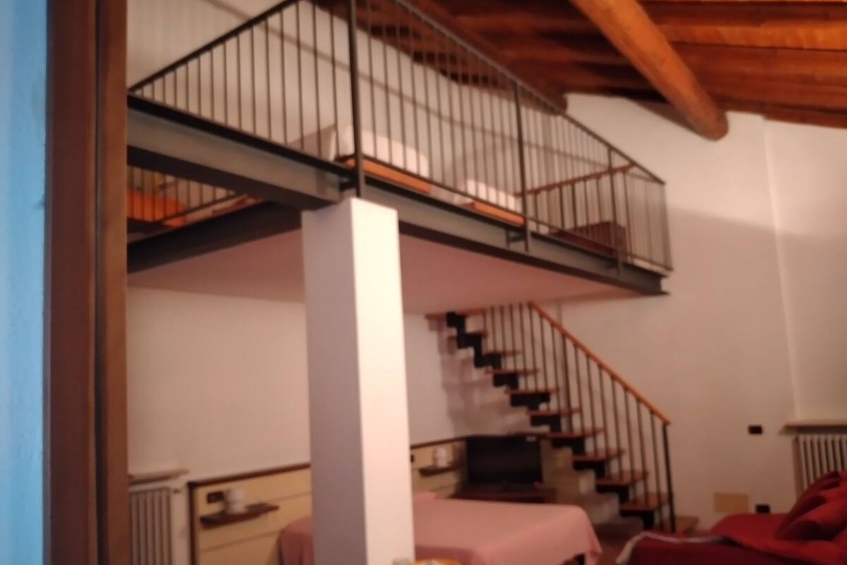 Une pièce avec un escalier, un lit, un bureau et une chaise.