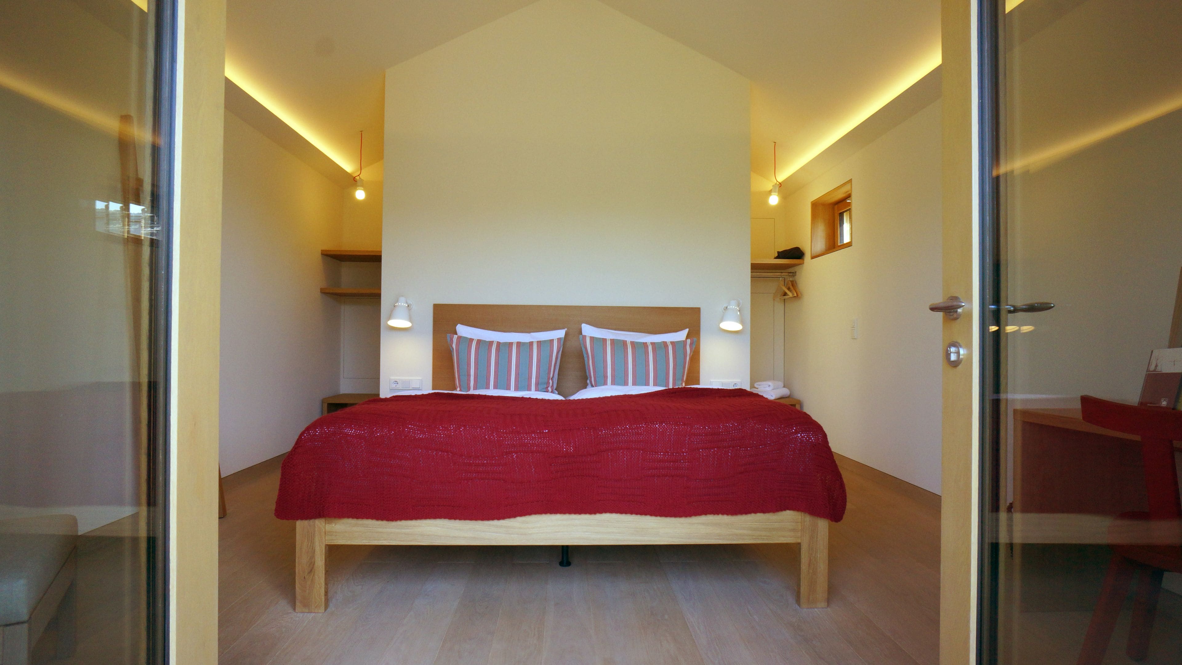 A modern bedroom with a large bed, bedside lamps, and a wooden headboard.
