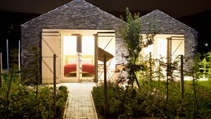 A stone building with two open doors leading to a bed and a seating area. - WeinKulturgut Longen-Schlöder (Longuich)