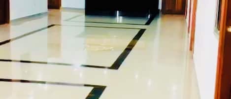 A spacious hotel lobby with a central reception desk, a polished floor, and a modern ceiling design.