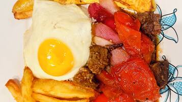 Un plato con un huevo frito, bistec, pimientos rojos y papas fritas.