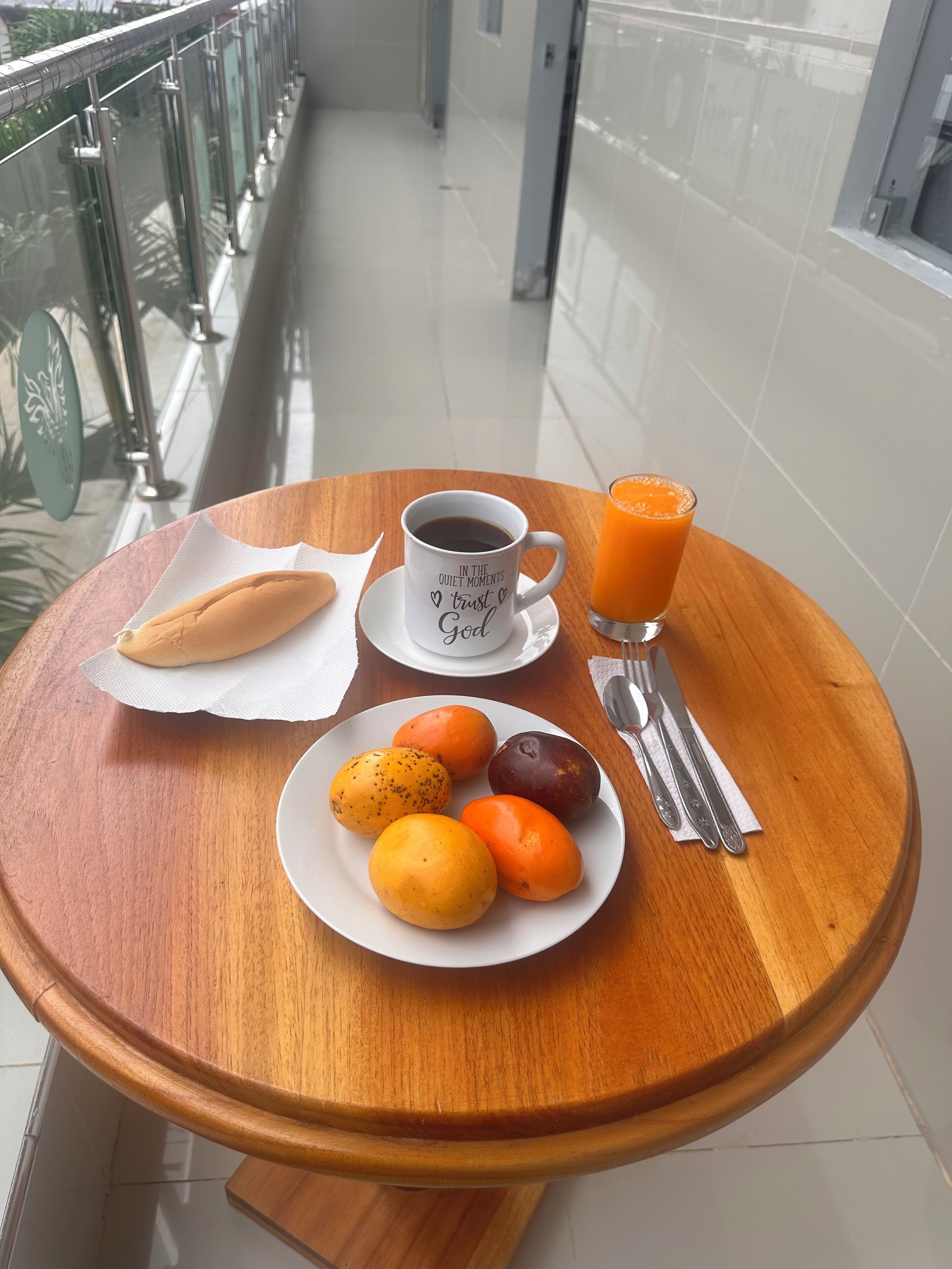 Een ontbijttafel met een fruitschaal, een kop koffie en een glas sinaasappelsap.