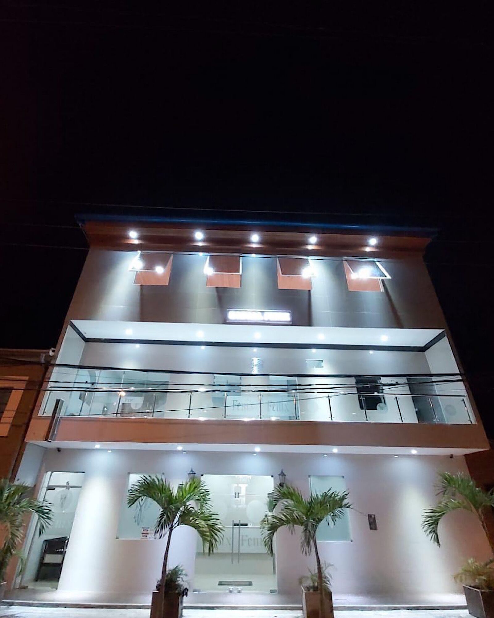 A modern hotel with a glass facade, multiple floors, and a well-lit entrance.