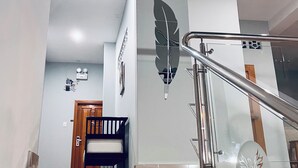 A modern bathroom with a large mirror, a wooden door, and a staircase with a metal railing. - Hotel Fenix (Iquitos)