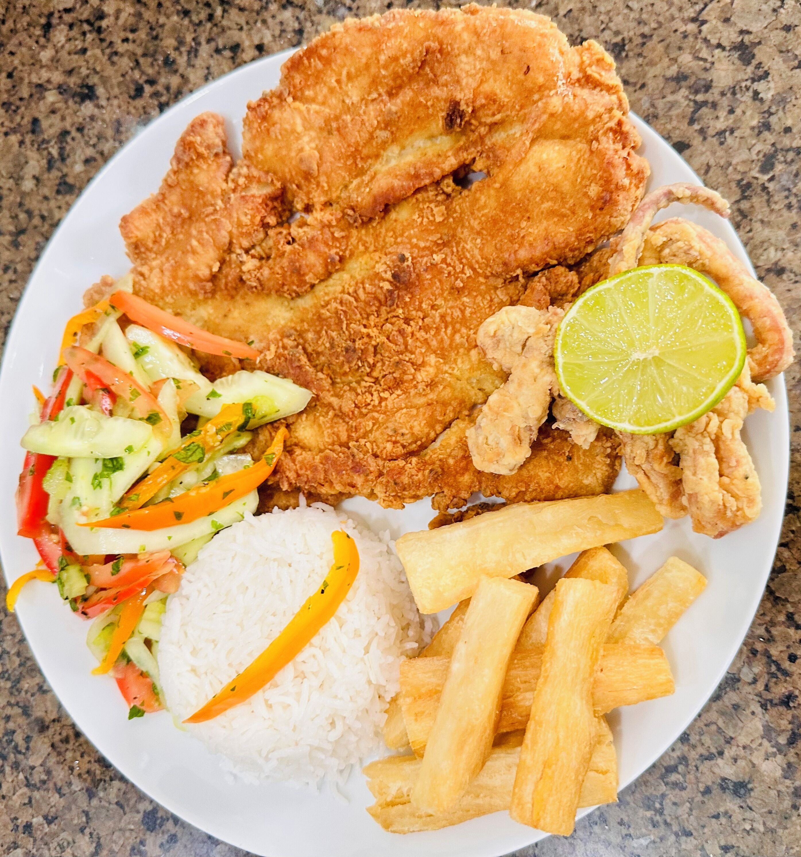 A plate with fried fish, rice, French fries, and a salad.