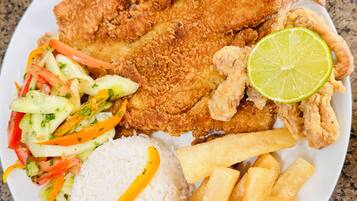 A plate with fried fish, rice, French fries, and a salad.