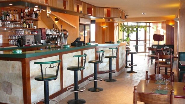 A bar area with stools, a counter, and a dining area with tables and chairs.