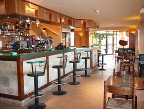A bar area with stools, a counter, and a dining area with tables and chairs. - Relais des Cinq Routes (Parnac)