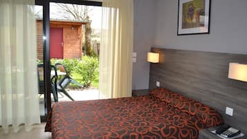 Relax in a spacious room with a large bed, wooden headboard, and bedside lamps.