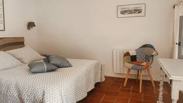Un dormitorio con una cama, una silla, un radiador y un cuadro en la pared.