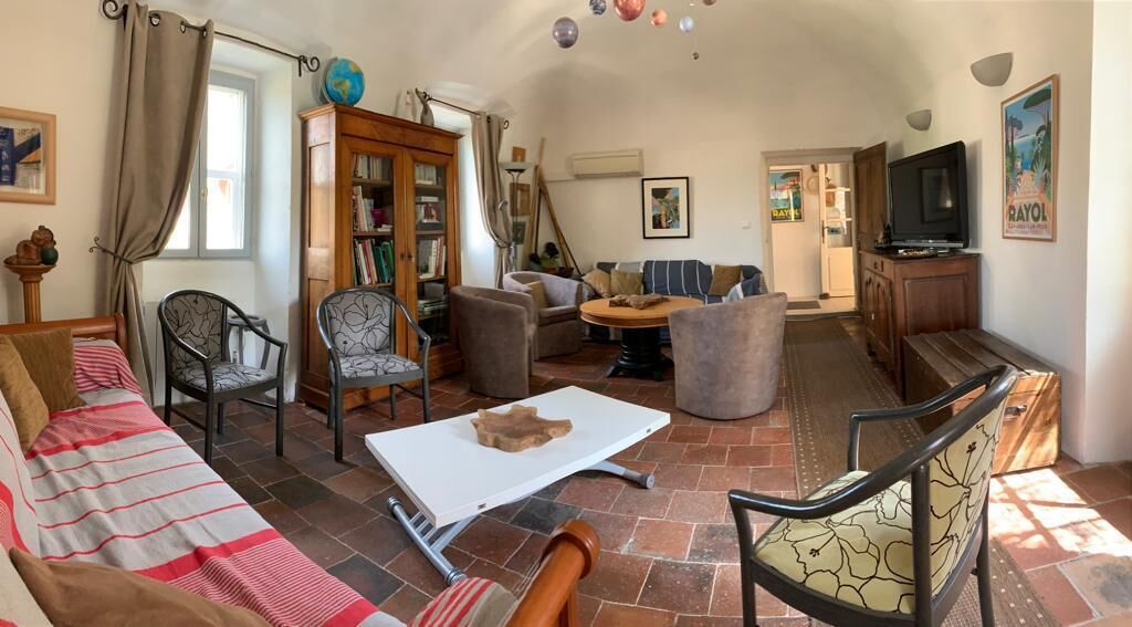 Uma sala de estar aconchegante com um sofá, cadeiras, uma mesa de centro e uma televisão.