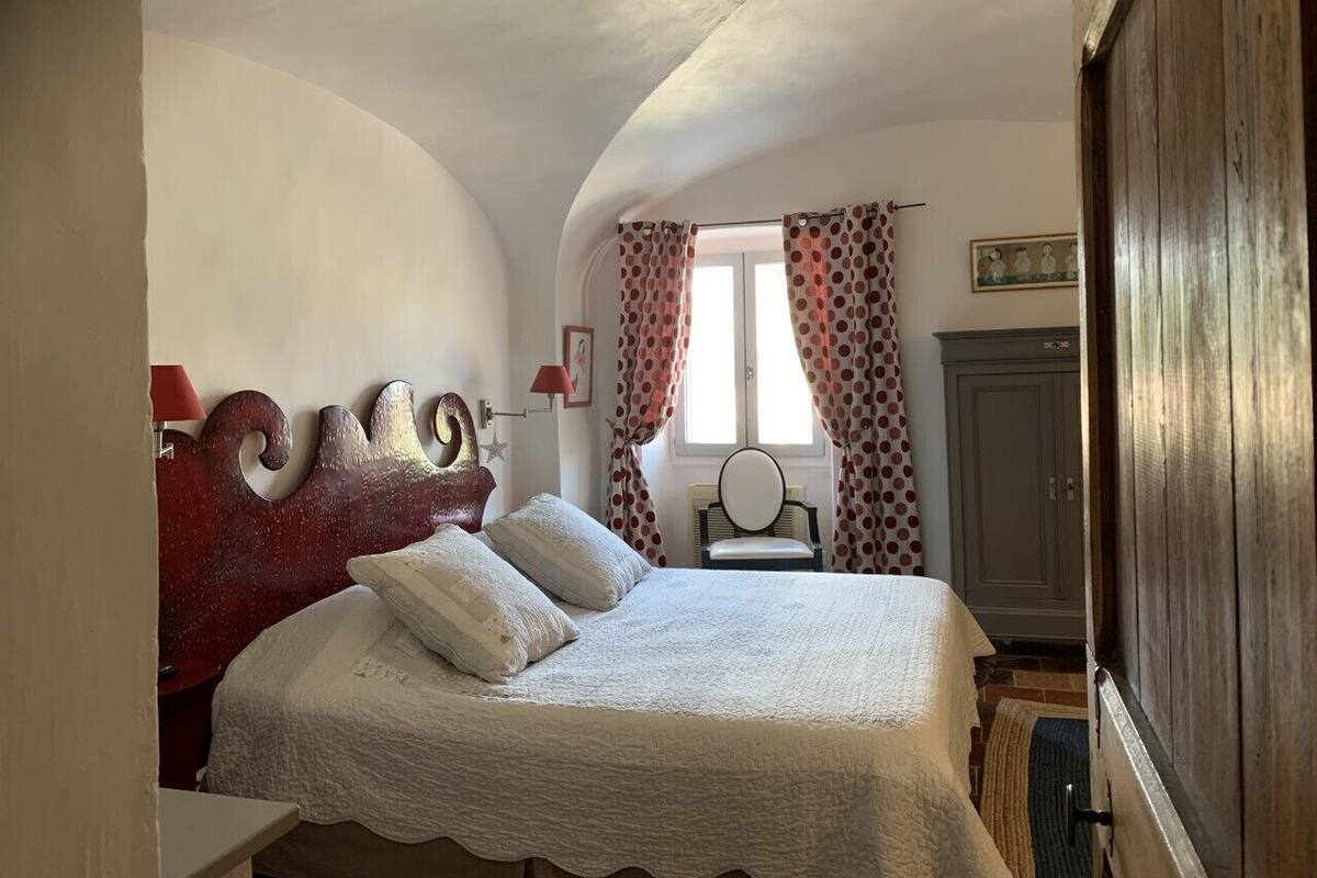 Un dormitorio con techo curvo, una cama con cabecera de madera, una silla y un armario.