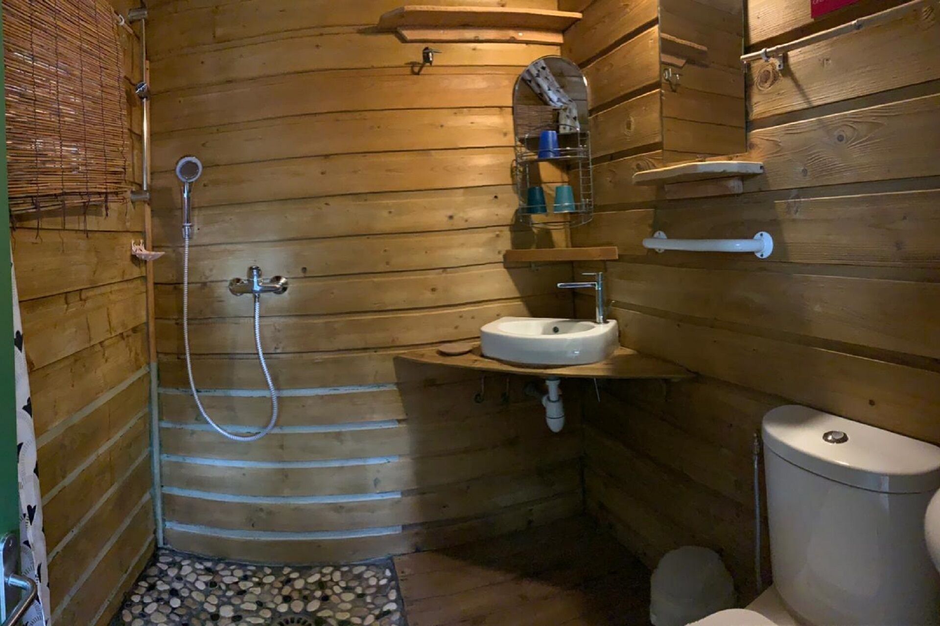 A wooden bathroom with a shower, sink, and toilet.