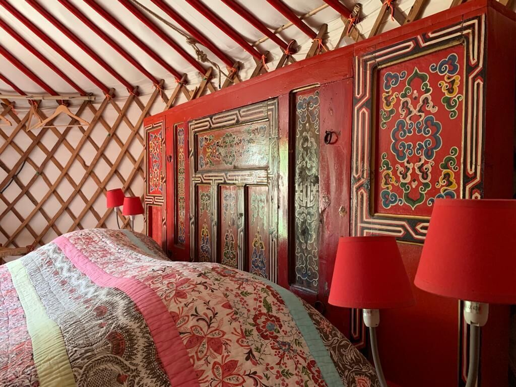 Een kamer met een kamertextiel met patroon, rode wanden en traditionele houten deuren met gedetailleerd ontwerp.