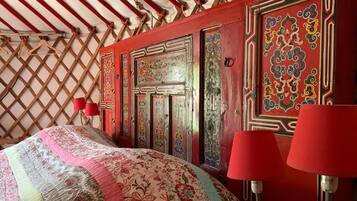 Een kamer met een kamertextiel met patroon, rode wanden en traditionele houten deuren met gedetailleerd ontwerp.