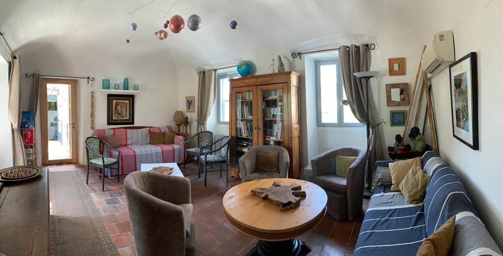 Una sala de estar acogedora con un sofá, sillones, una mesa redonda de madera y una estantería.