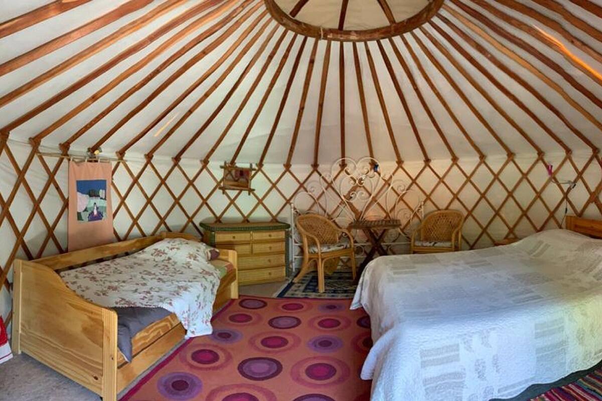 Una yurtas con dos camas de madera, una mesita y una silla.