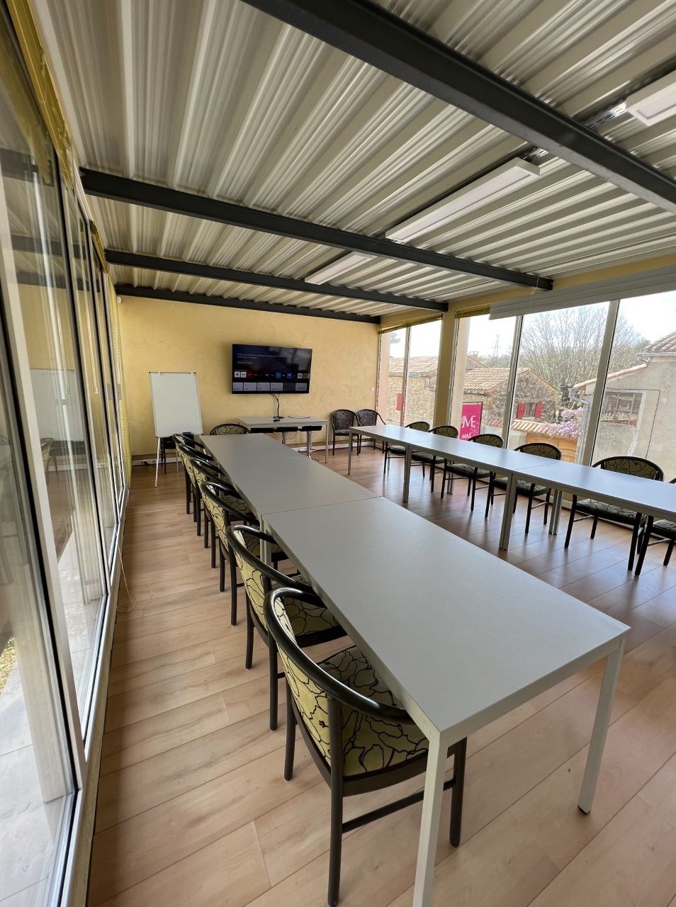 A conference room with a long table, chairs, a whiteboard, and a TV screen.