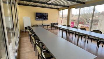A conference room with a long table, chairs, a whiteboard, and a TV screen.