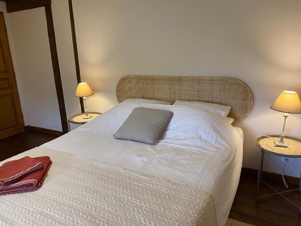 A neatly made bed with a pillow, two bedside lamps, and a folded towel on the floor.