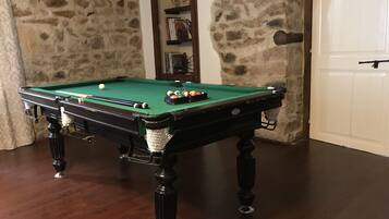 A pool table with balls, a cue stick, and a billiard rack.