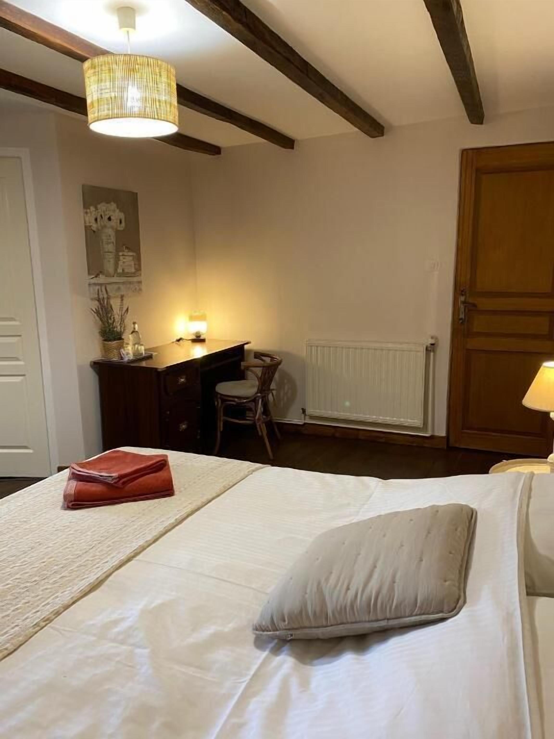 A bedroom with a bed, a desk, a chair, and a lamp.
