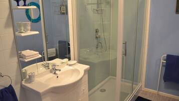 A bathroom with a glass-enclosed shower, a white sink, and a mirror.
