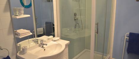 A bathroom with a glass-enclosed shower, a white sink, and a mirror.