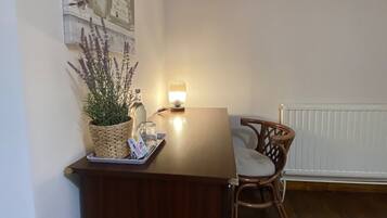 Een kamer met een houten eettafel, een rieten mand met planten, een kleine lamp en een stoel.