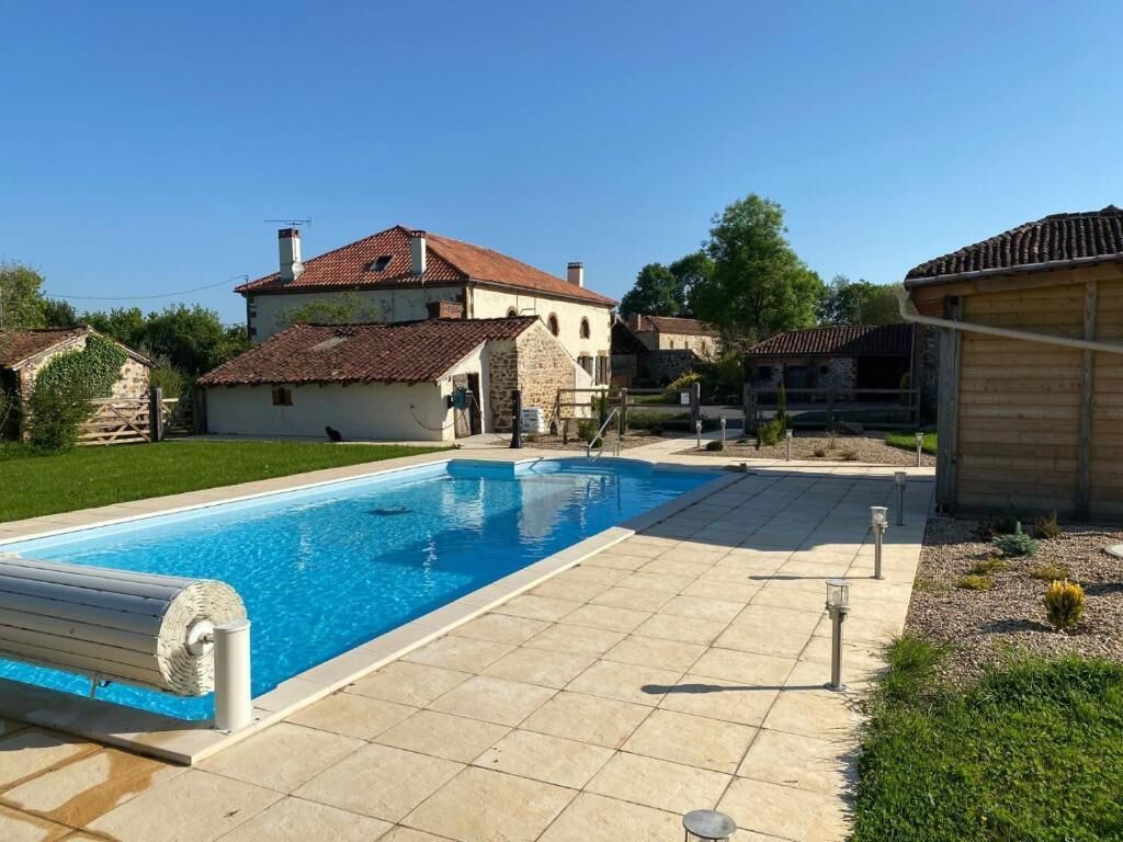 A swimming pool with a tiled deck, surrounded by houses with red-tiled roofs.