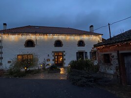 A white building with a tiled roof, arched windows, and a lit entrance.