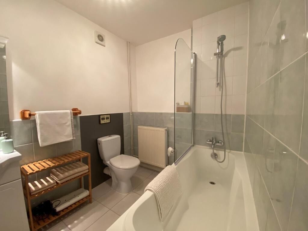 Ein Badezimmer mit Badewanne, Toilette und einem Holzboden mit Handtüchern.