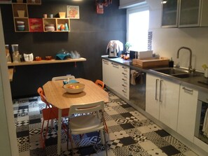A kitchen with a checkered floor, a wooden table, and a bowl of fruit. - Bed and Breakfast New Morning (Rome)