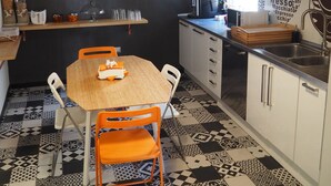 A compact kitchen with a wooden table, orange chairs, a coffee machine, and a black and white patterned floor. - Bed and Breakfast New Morning (Rome)