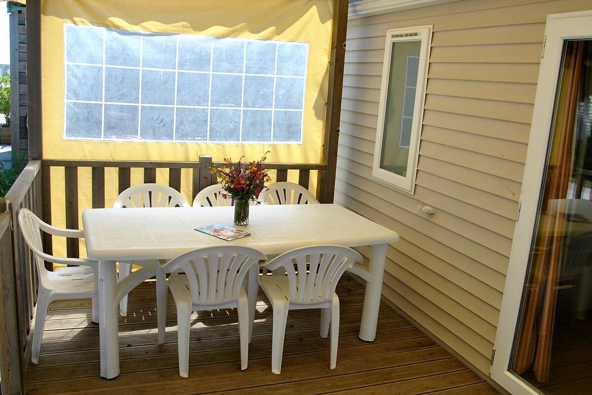 A covered outdoor dining area with a table and chairs, a window, and a door.