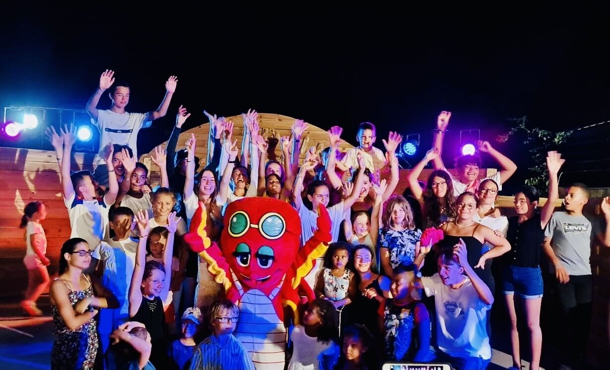 Un grupo de personas reunidas al aire libre de noche, con un personaje inflable gigante en el centro.