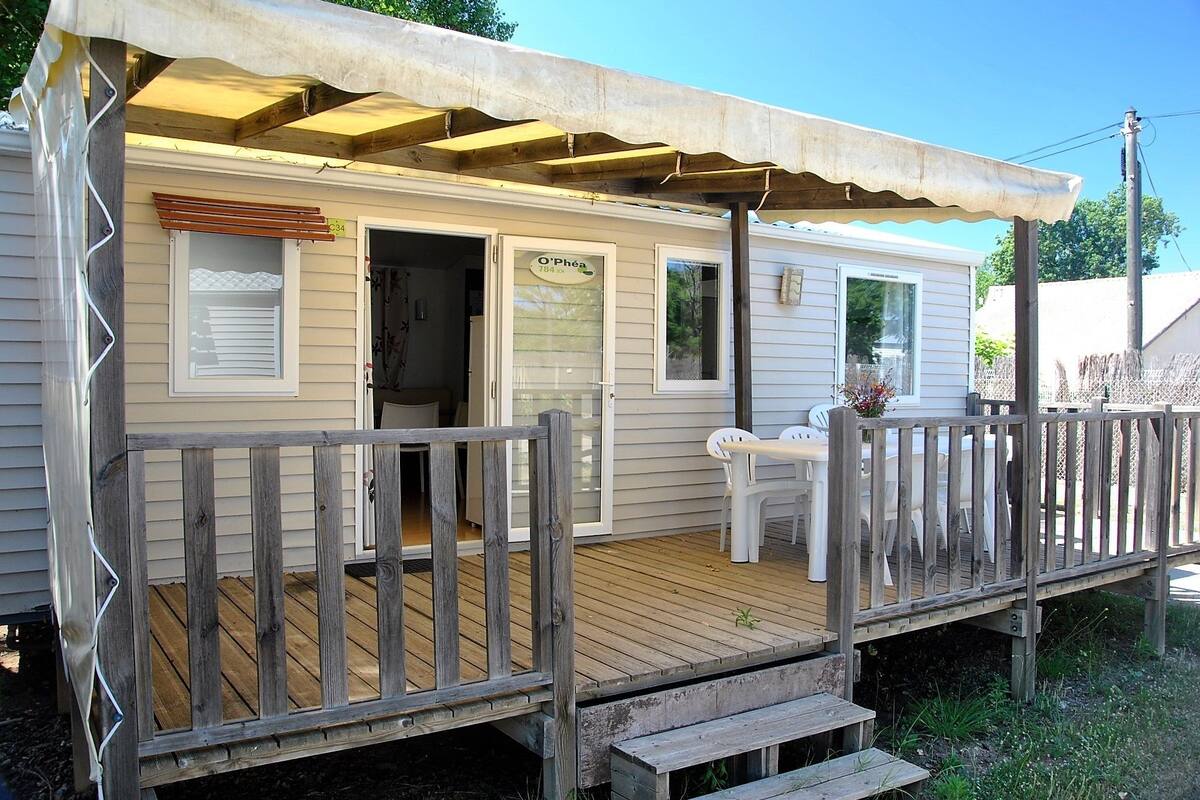 A mobile home with a wooden deck and a covered porch.