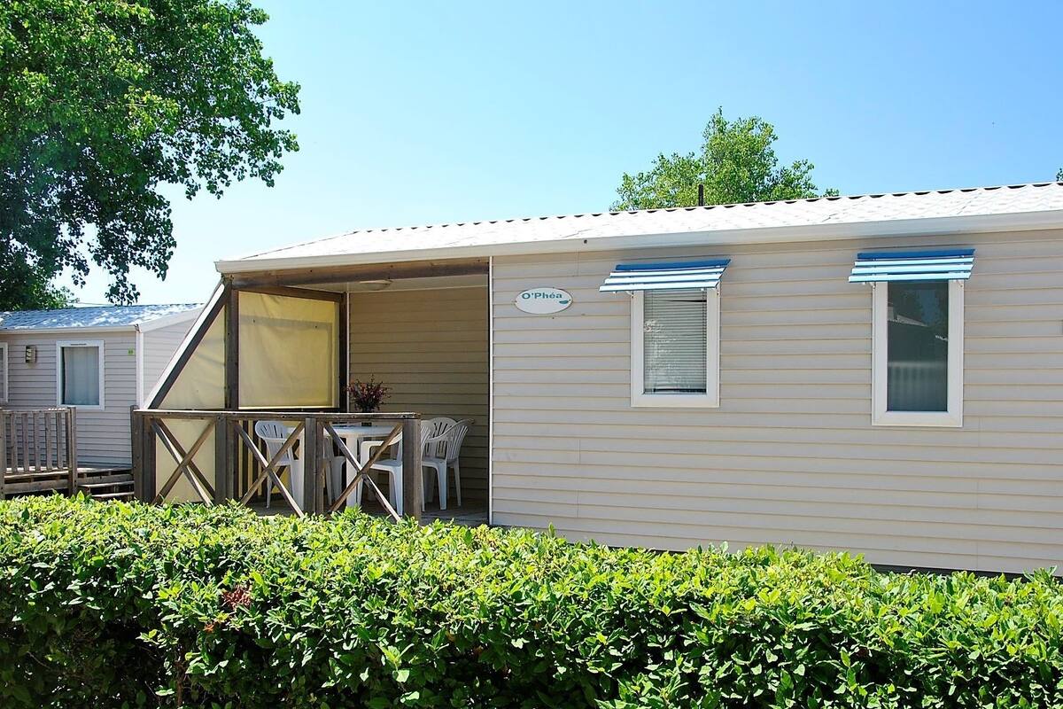 A mobile home with a patio area, a small table, and two chairs.