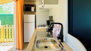 Una piccola cucina compatta con lavello in acciaio inox, forno a microonde e piano cottura a gas.