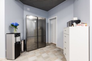 Compact kitchen area with a refrigerator, water dispenser, and ample storage.