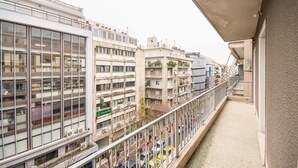 A multi-story building with large windows and balconies, featuring a pedestrian walkway and parked cars below. - Victoria Queens Paradise Apartments (Athens)