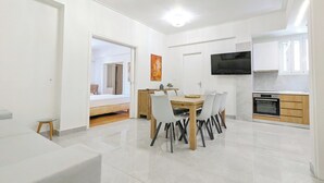 Um apartamento moderno e bem iluminado, com área de jantar, cozinha e um quarto visível por uma porta aberta.